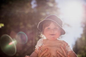 held up toddler, smiling, looking into camera, backlight, held up toddler, smiling, looking into camera, backlight,